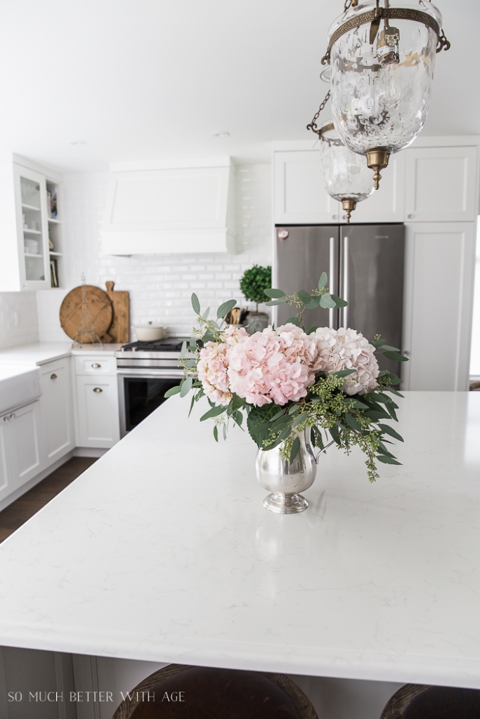 Pink peonies and eucalyptus in vase on large kitchen island.