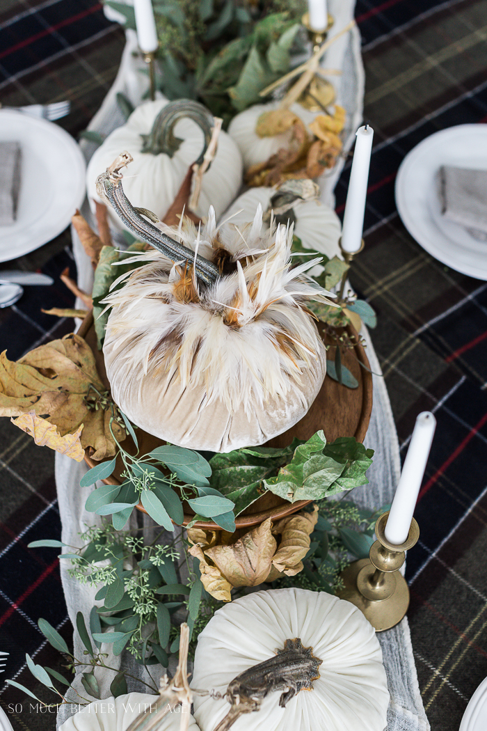 White velvet pumpkins with feathers on DIY centerpiece on table.