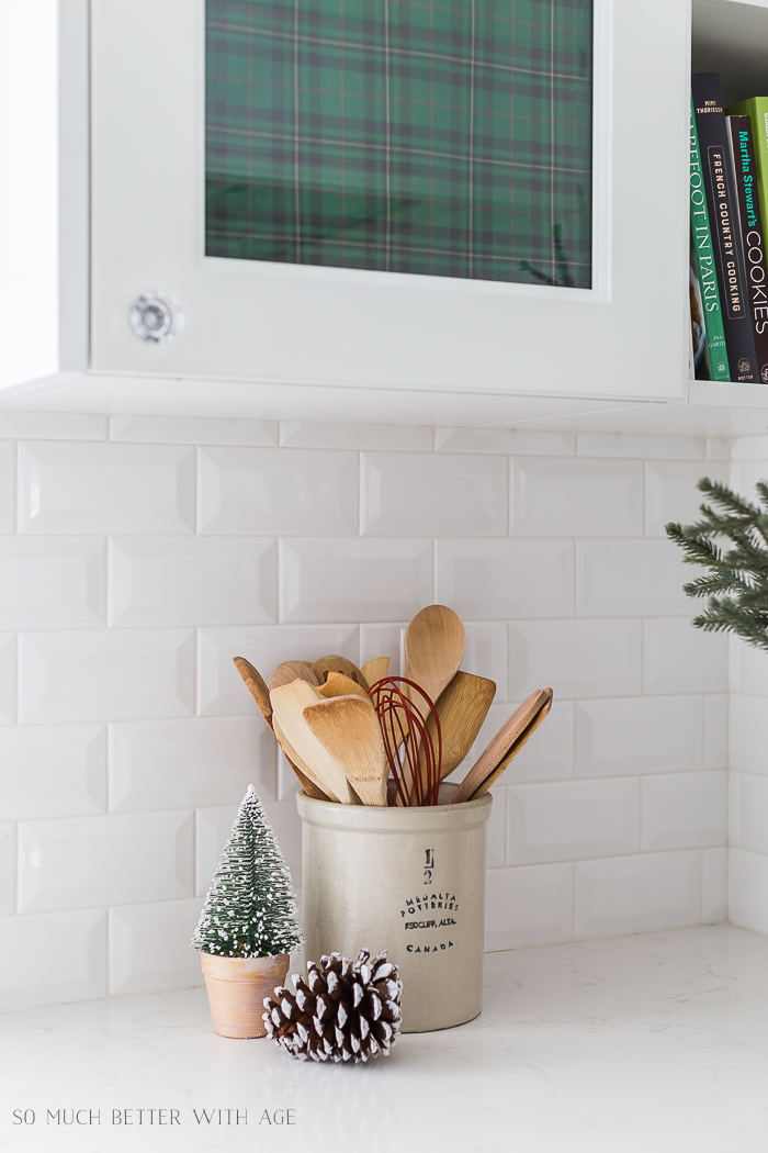 Wooden spoons and flocked pinecones and mini tree on the counter.