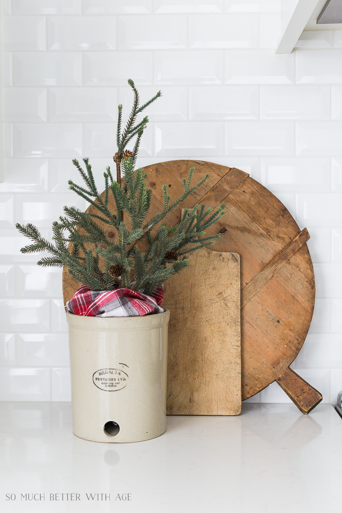 Wooden bread and cutting boards with a mini evergreen tree in a crock on the counter.