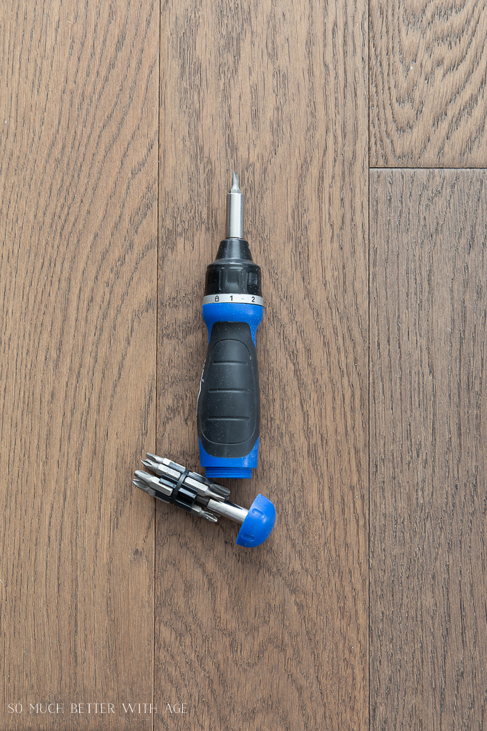 A blue and black ratchet screw driver on the floor.