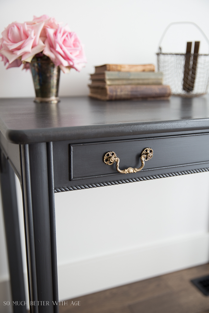 The grey table with a brass ornate pull on it.