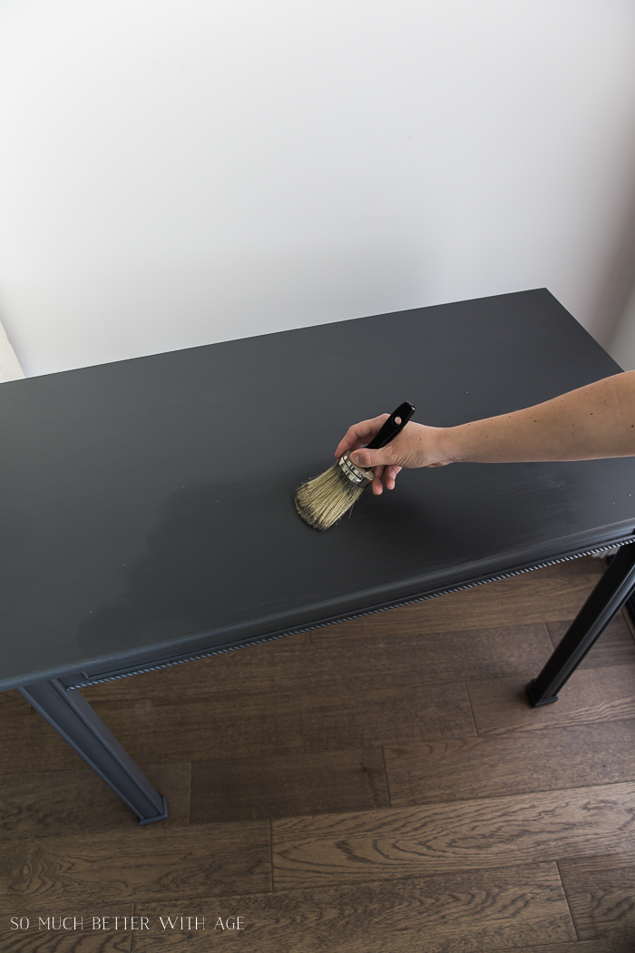 Applying wax to a dark grey table.