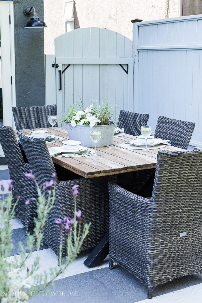 Outdoor table set for a meal with lavender and grey fence.