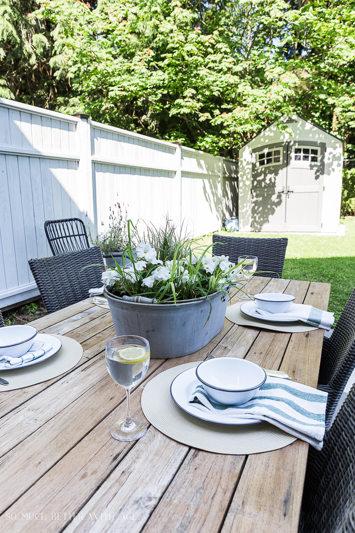 Outdoor table setting with grey painted fence.