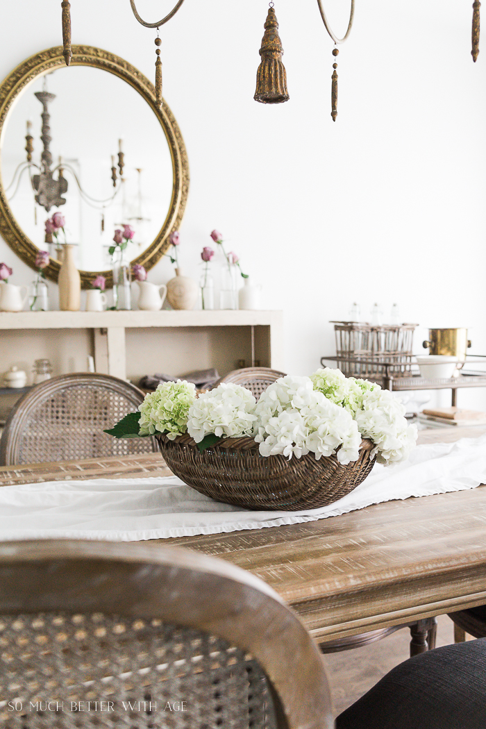 Wooden table and chairs with white runner on table.
