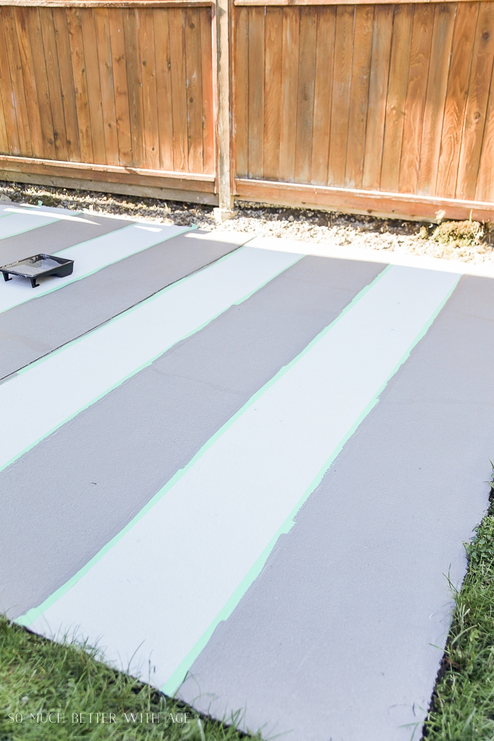 Painting stripes on concrete with a wooden fence beside it.