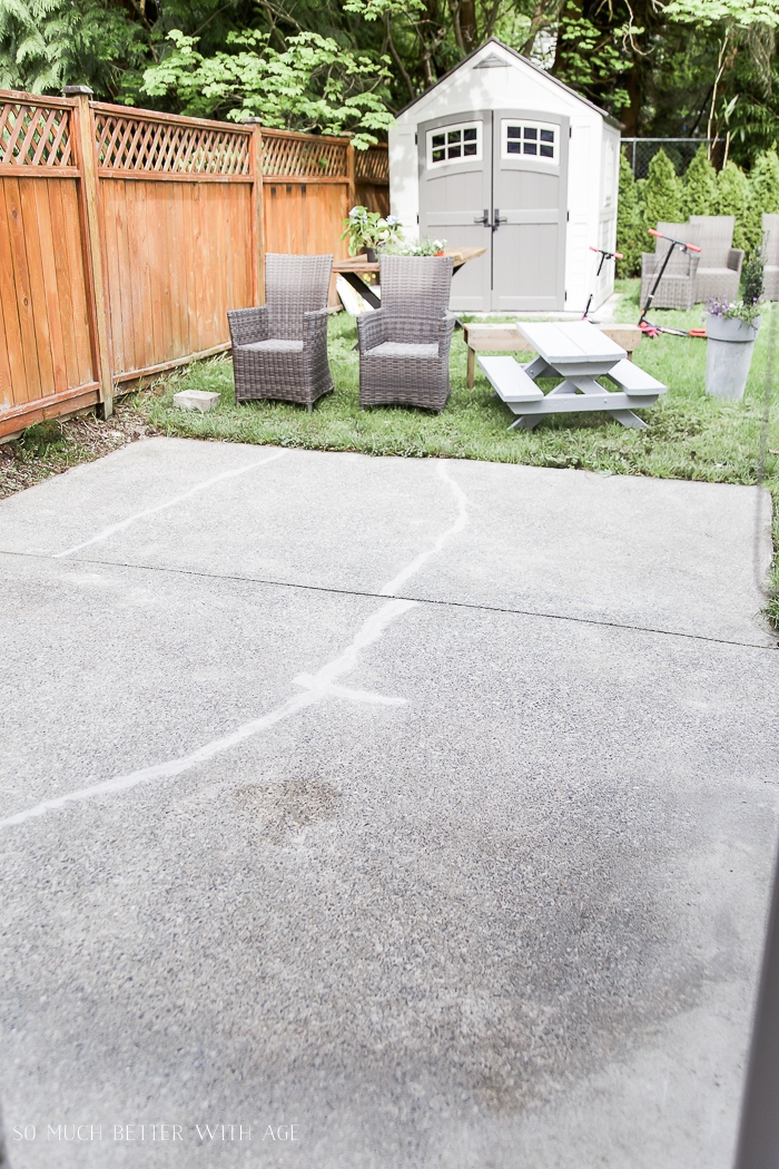 Clean concrete patio with furniture in grass in backyard.