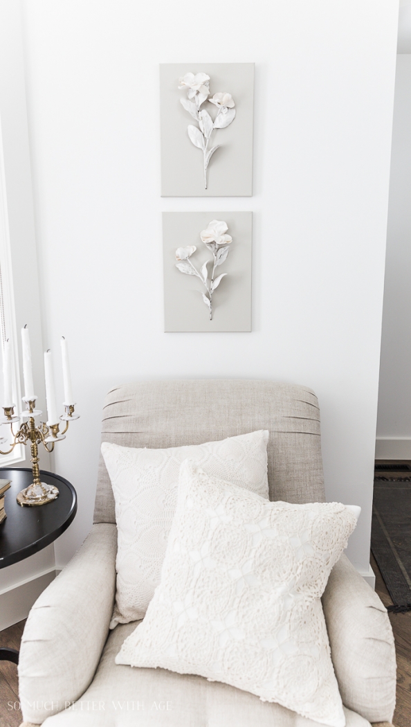 Linen chair with flower art on wall.
