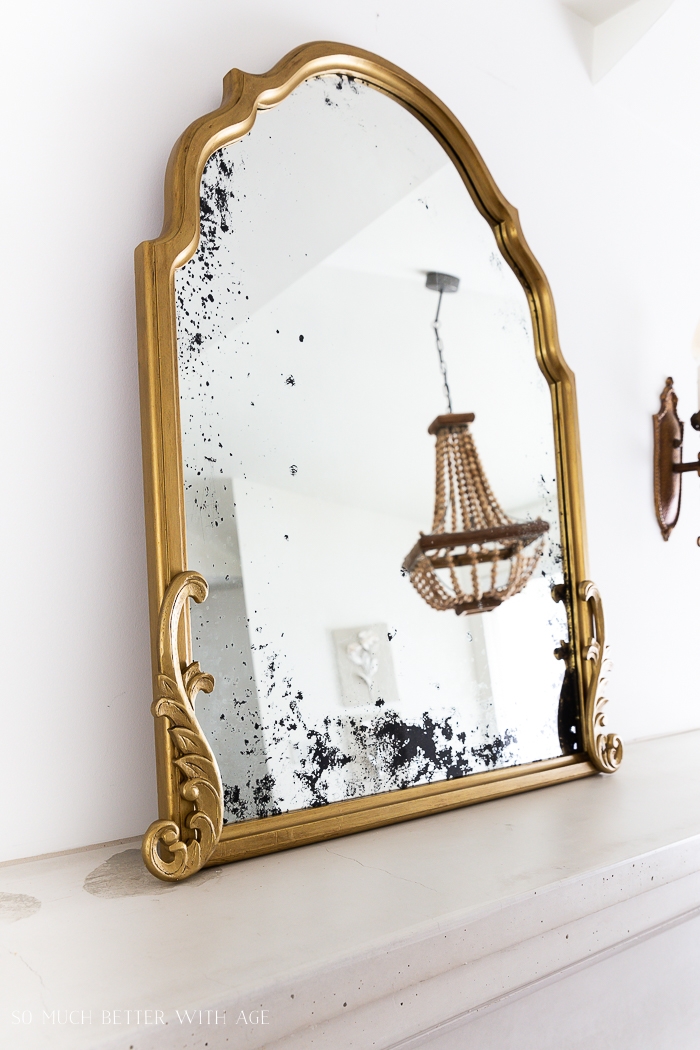 Gold mirror with image of beaded chandelier. 