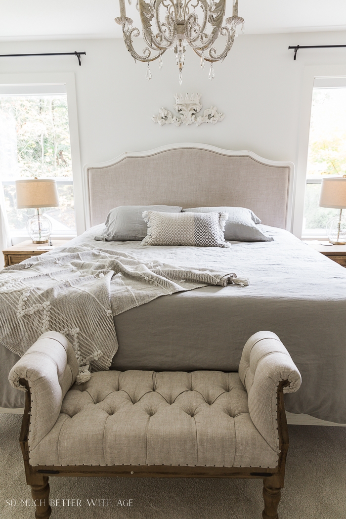 Upholstered bed with tufted ottoman at foot of it. 