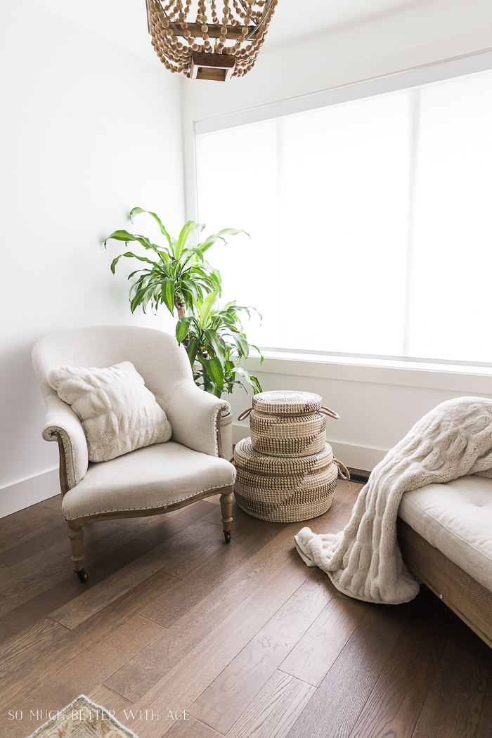 Linen covered chairs with fluffy throw blanket and pillow with green plant in corner. 