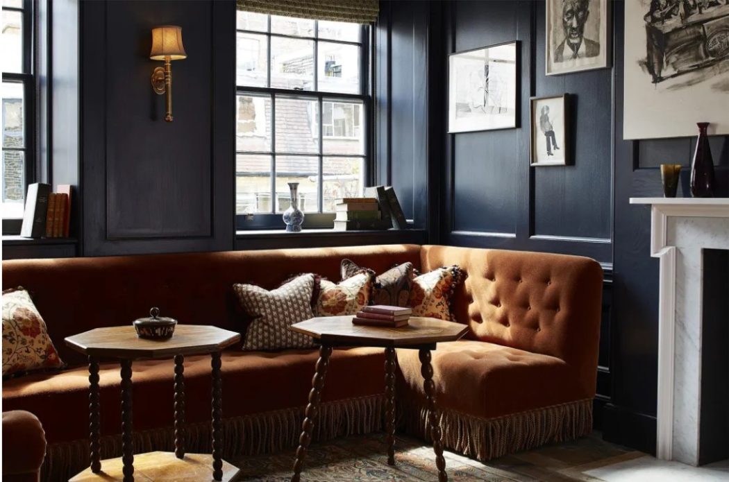 Dark blue walls with velvet orange tufted bench seating.