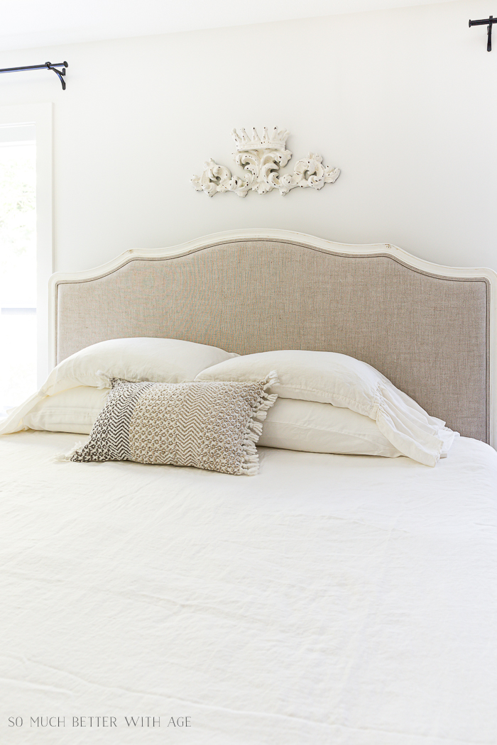 Linen headboard with crown-like art on wall. 