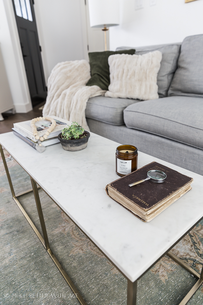 Sala com sofá cinza e mesa de centro em mármore.