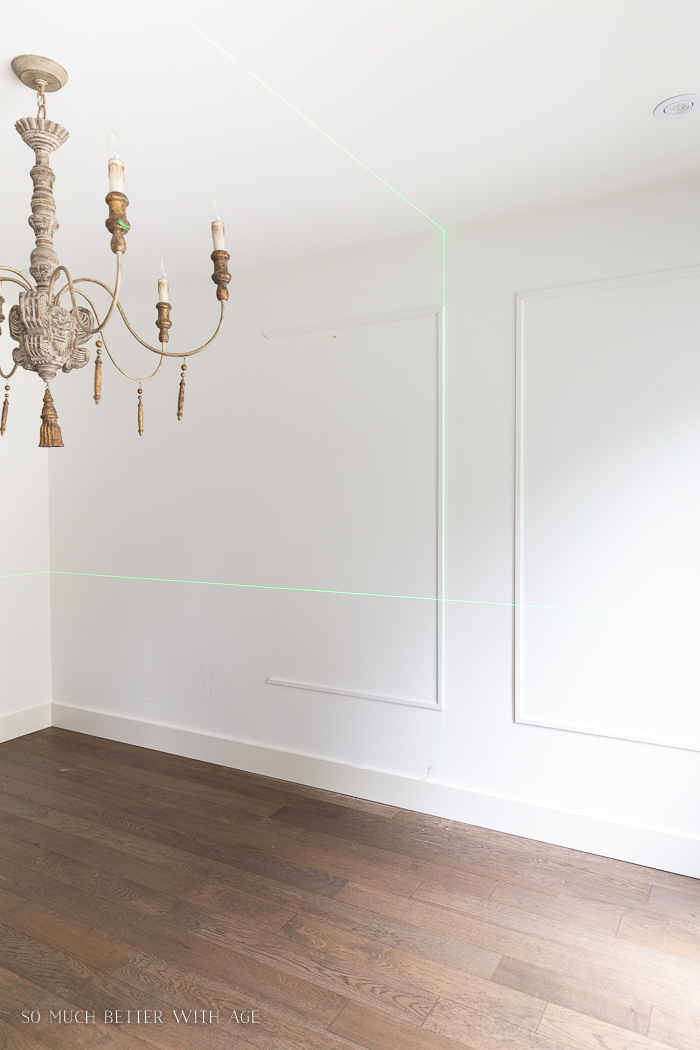 French chandelier with moulding on wall and laser level lines on wall.