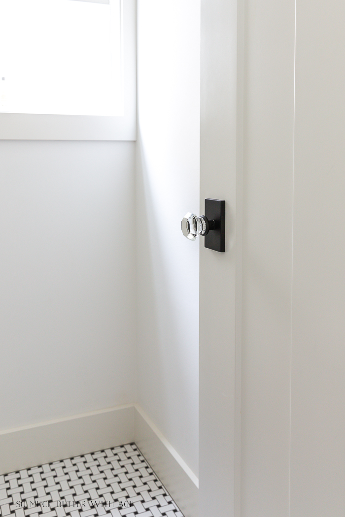 Glass doorknob in bathroom with black and white floor tile. 