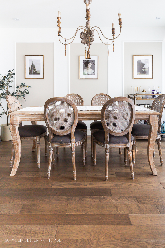 Dining room with artwork in gold frames and large wooden chandelier. 