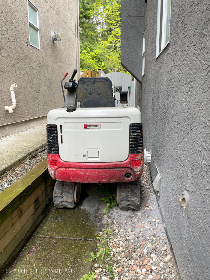 Small excavator going down side of house.
