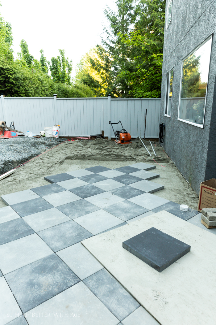 Laying down the checkerboard tile in the backyard.