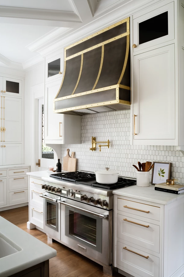 Kitchen by Britt Design Studio with metal black and brass hood range. 