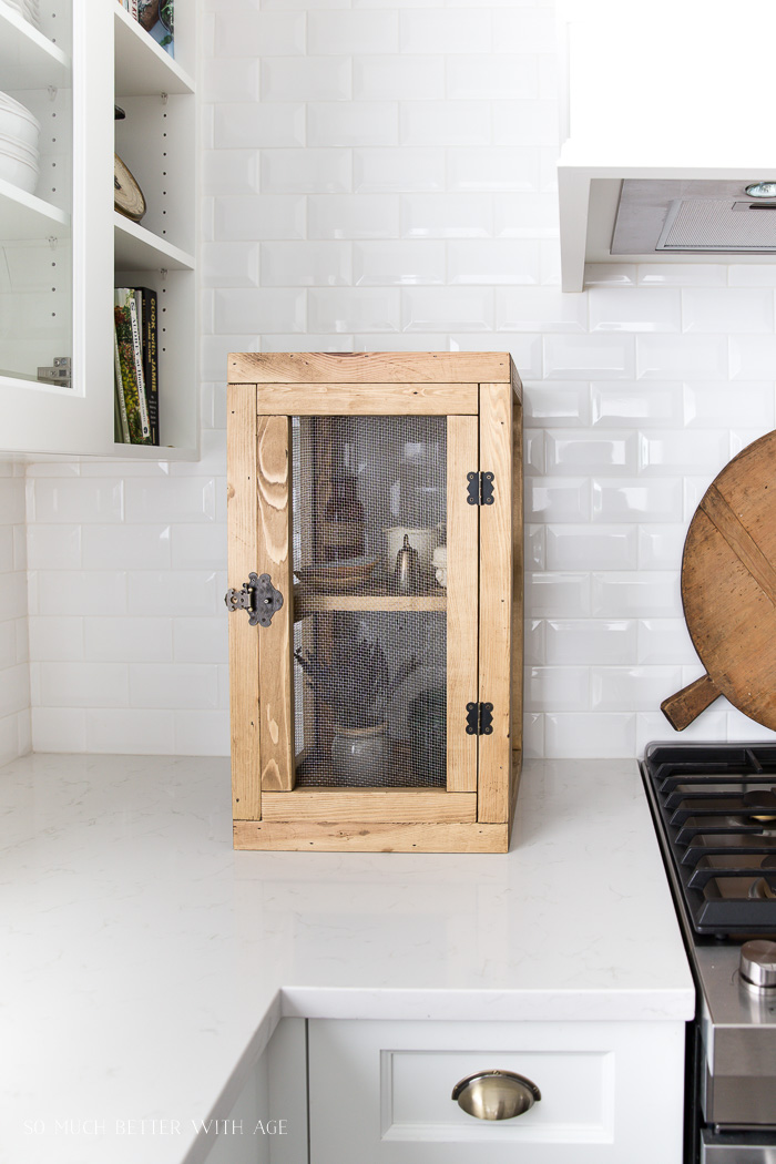 Wooden display case in kitchen with mesh screens. 