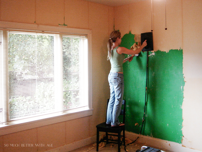 Girl using a wallpaper steamer to remove wallpaper from a wall. 
