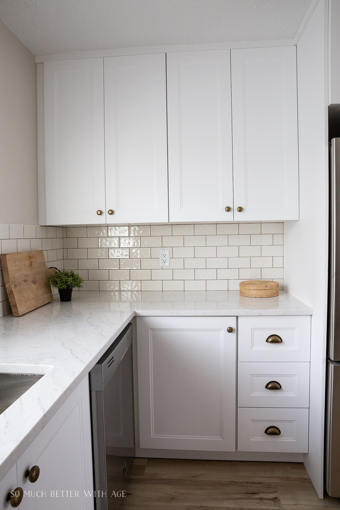 Ikea kitchen cabinets all white with creamy backsplash tiles. 