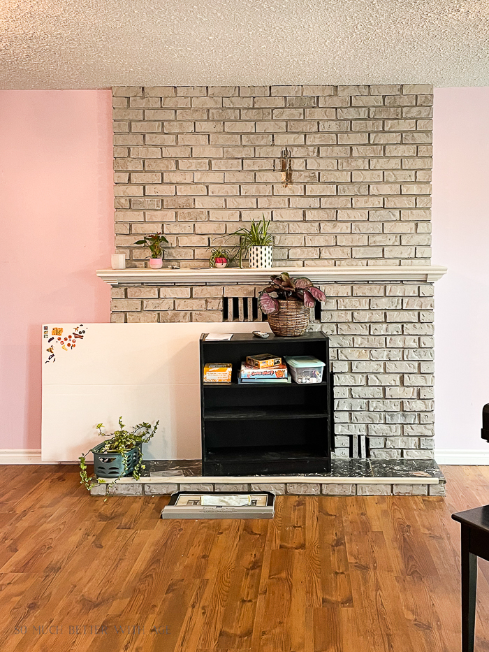 Before photo of brick fireplace with pink painted walls. 