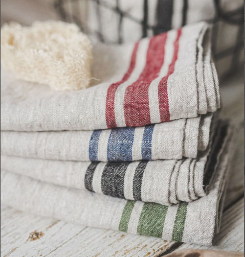 Stack of 4 linen tea towels in a beautiful beige linen color with one in a red stripe, one with a blue stripe, one with a black stripe, and one with a green stripe. 