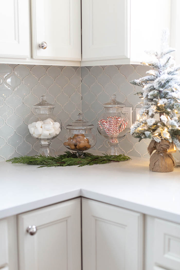 Glass jars full of candy canes and marshmallows and gingerbread in kitchen. 