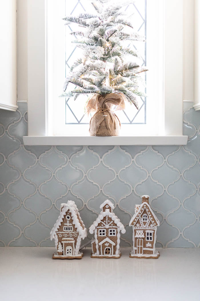 Mini flocked Christmas tree in front of lead window and mini gingerbread houses. 