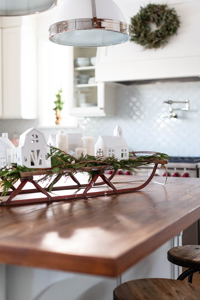Vintage sled/sleigh on kitchen island with cedar and Christmas village. 