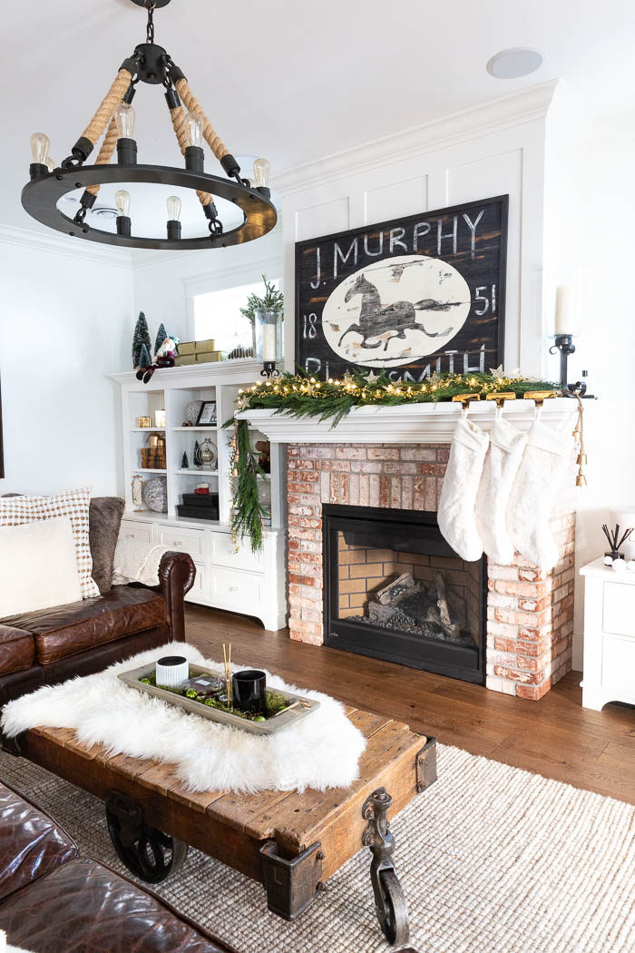 Living room decorated for Christmas with leather sectional and rustic touches. 