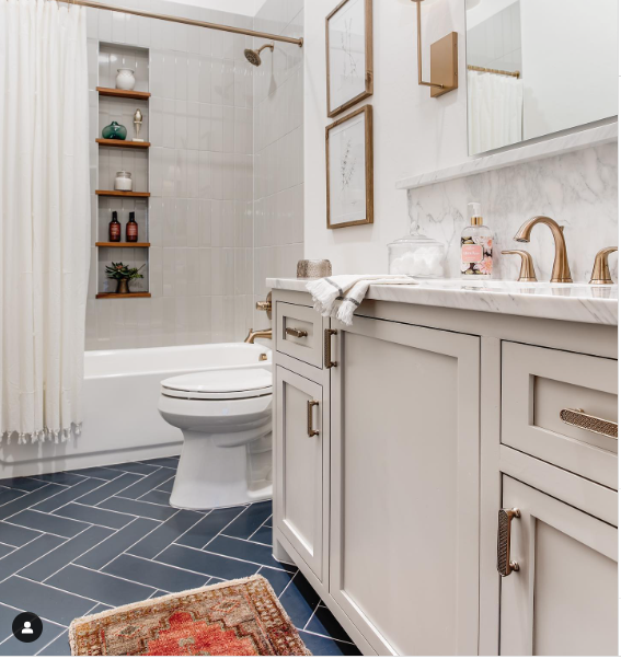 Painted bathroom cabinets in Worldly Gray by Sherwin Williams. Grey herringbone tiled floors. 