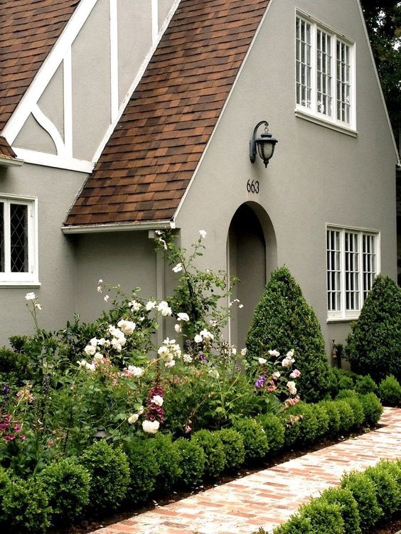 Dark beige character home with white trim and beautiful garden. 