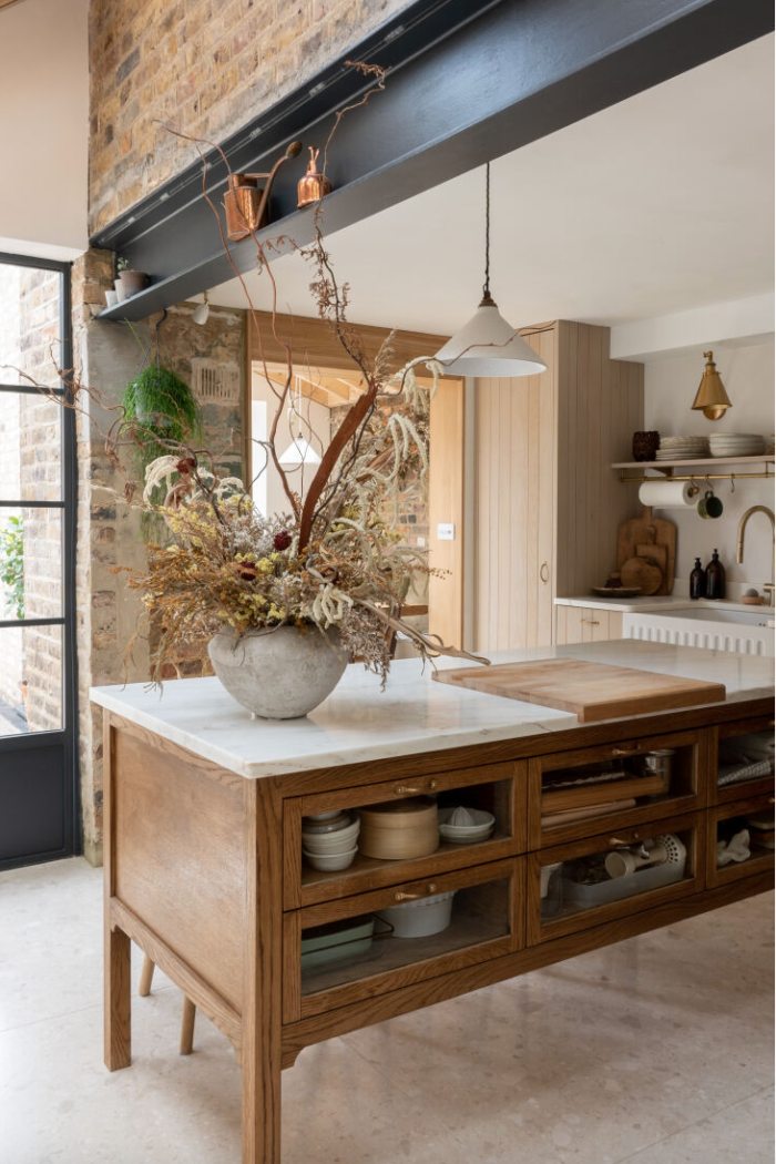 Kitchen with exposed brick and metal beams and oak cabinetry. 