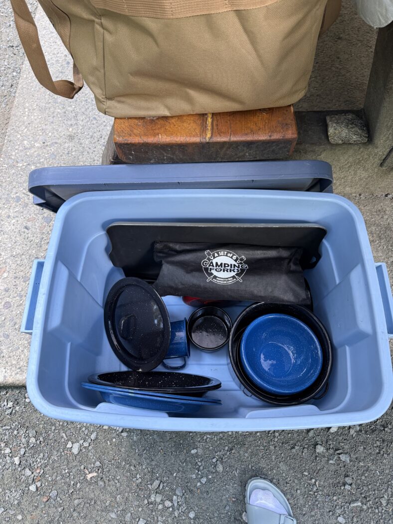 Camping plates, bowls, pots, pans in plastic blue bin.
