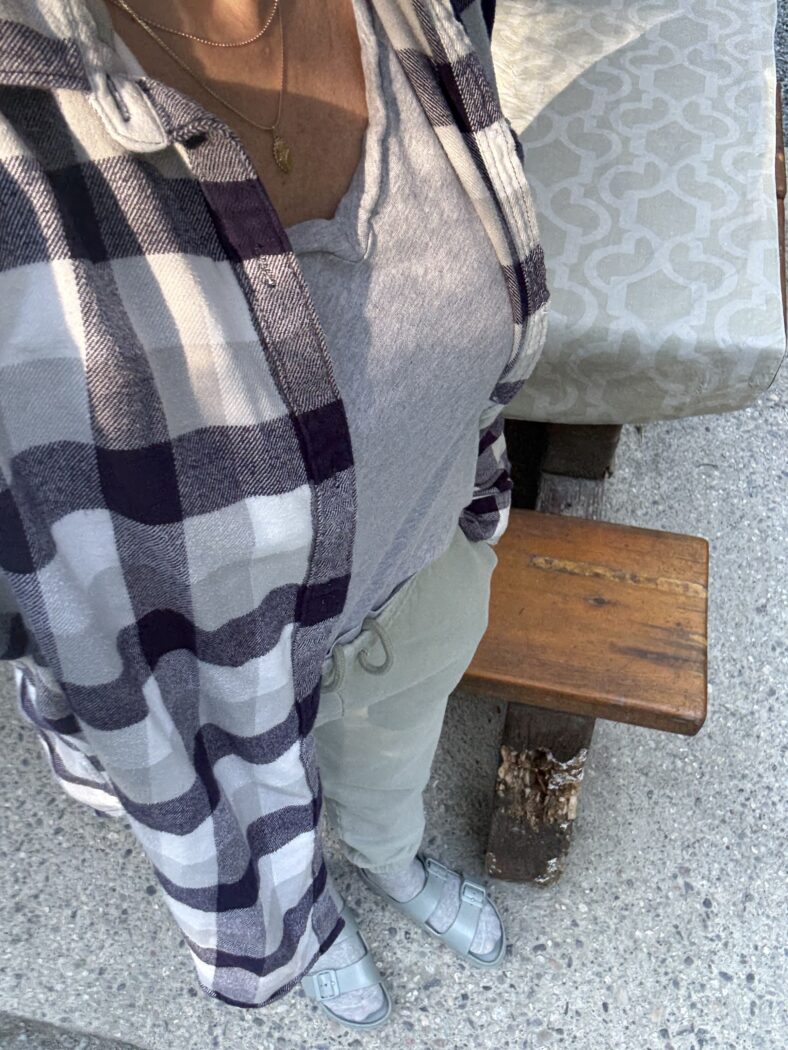 Selfie of woman camping in plaid shirt and sweat pants.