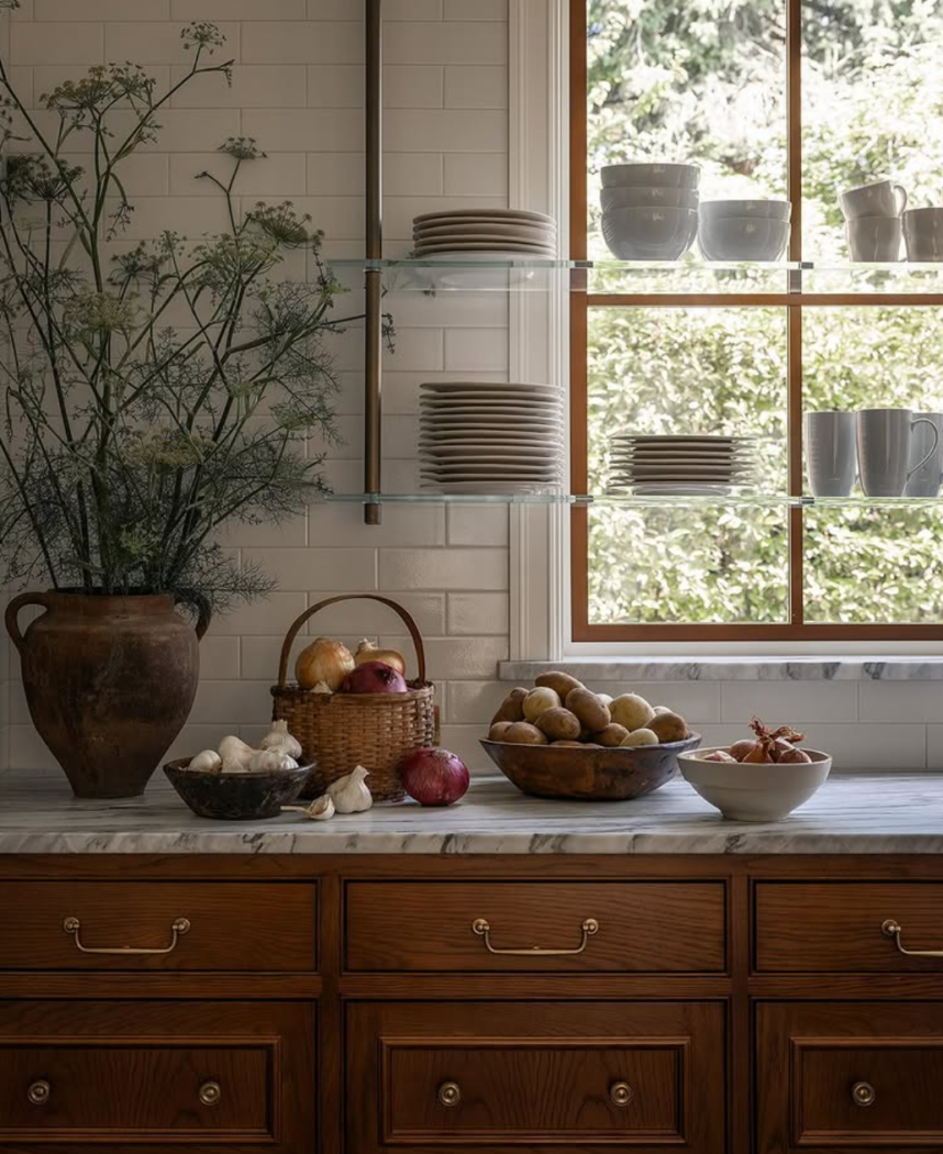 Glass and brass shelving in front of large kitchen window by Katie Leclerq.