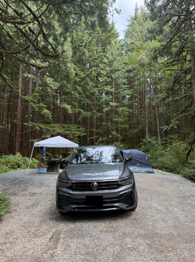VW SUV in campsite with tent and canopy over the picnic table.