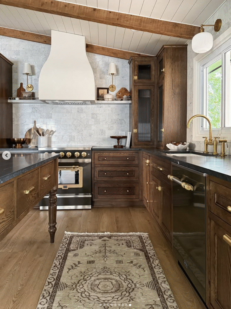 Stained wooden kitchen cabinets in kitchen with vaulted ceiling and plaster range hood. 