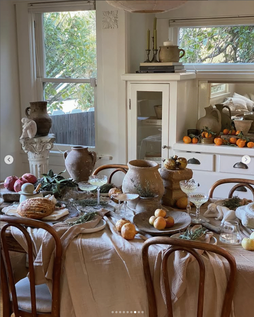 Tablescape with olive jars, fruit and champagne glasses over linen tablecloth. 