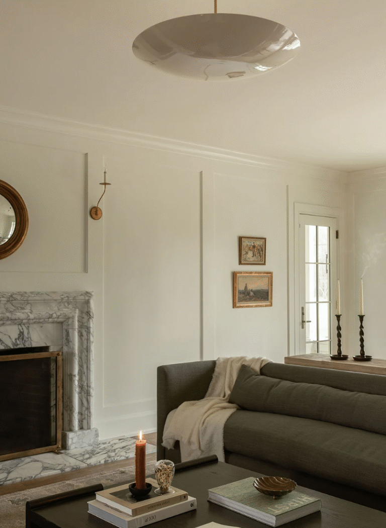 Living room with large beige glass pendant and grey sofa and marble fireplace.