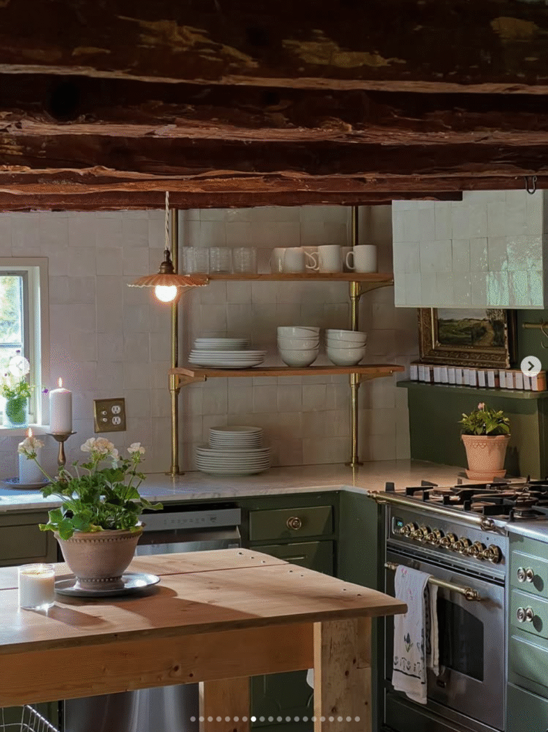 Old kitchen with large wooden beams and green kitchen cabinets and wooden kitchen island. 