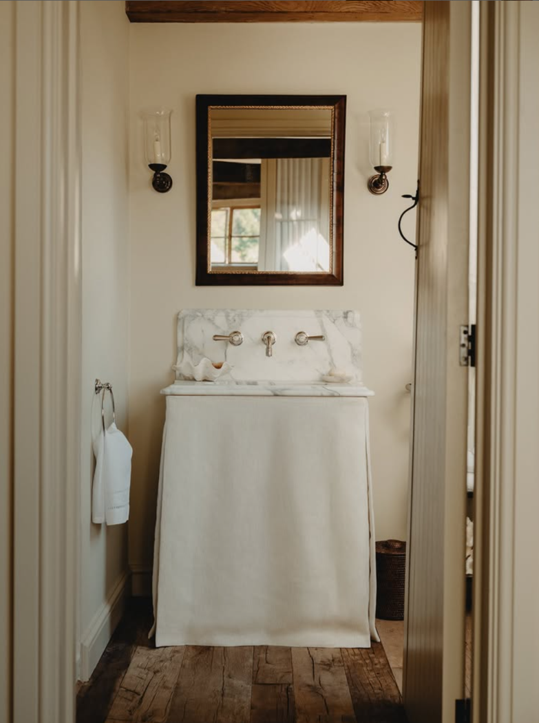 Marble sink in bathroom with linen skirt by Berkeley Hawkes.
