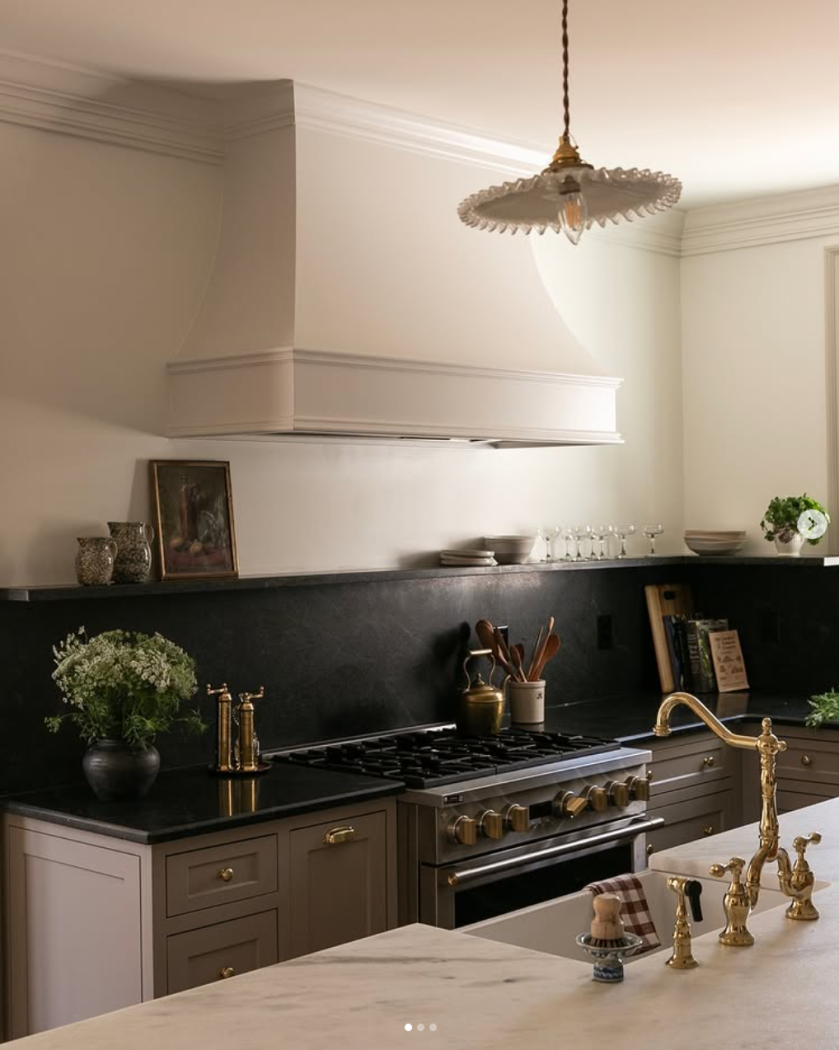 Kitchen with no upper cabinets, black soapstone counters and purple-brown cabinets.