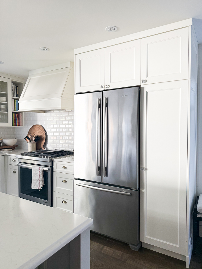 White cabinetry with stainless steel fridge and stove.