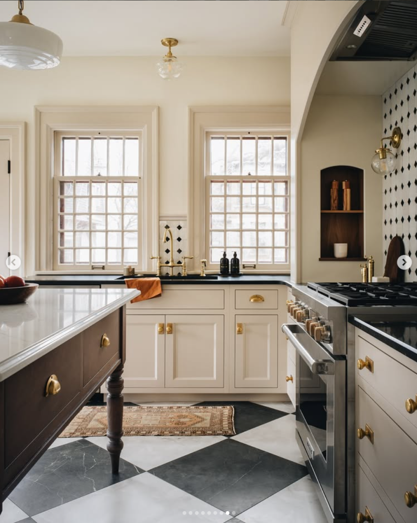 Cream kitchen inset cabinets with black and white large checkerboard tiles and milk glass light fixture. 