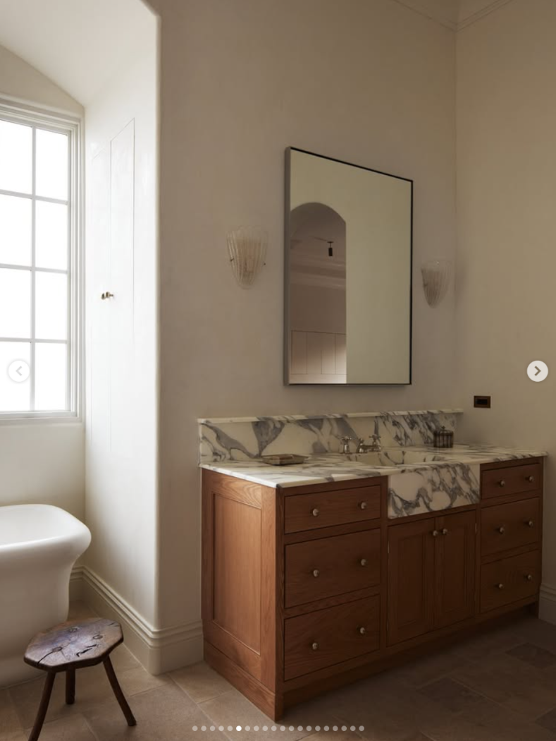 Wooden bathroom vanity with deep veining marble sink and countertop.